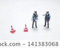 Miniature police officers stand near traffic safety cones. 141383068