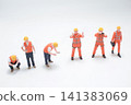 Miniature construction workers stand on plain white background. 141383069