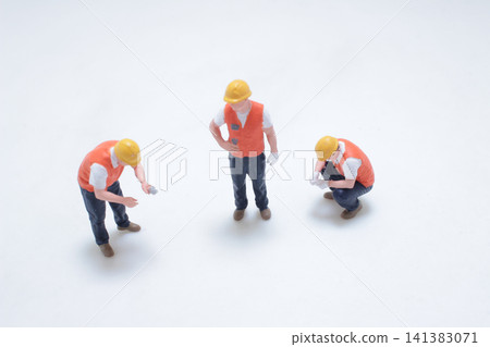 Miniature construction workers stand on plain white background. Miniature construction workers stand on plain white background. 141383071