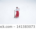 Miniature Shinto shrine maiden holds a sweeping broom. 141383073