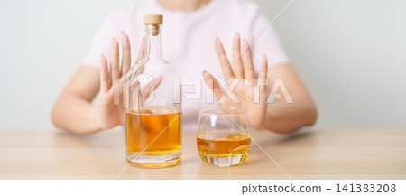 woman making stop hand gesture to refuse a glass of whiskey, Healthy man say no to alcohol drink, stop alcoholism and addiction concept. Responsible man reject a drink before driving and quit booze 141383208