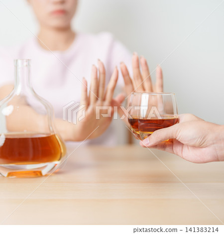 woman making stop hand gesture to refuse a glass of Cognac, Healthy man say no to alcohol drink, stop alcoholism and addiction concept. Responsible man reject a drink before driving and quit booze woman making stop hand gesture to refuse a glass of Cognac, Healthy man say no to alcohol drink, stop alcoholism and addiction concept. Responsible man reject a drink before driving and quit booze 141383214