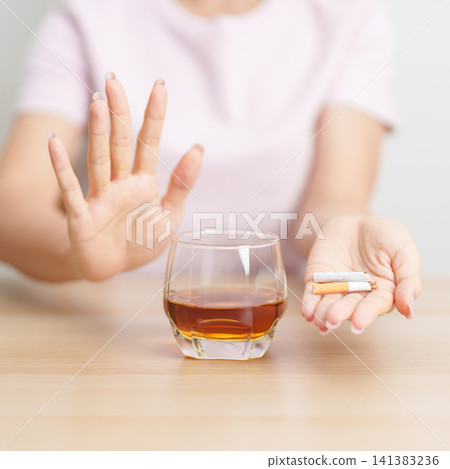 woman hand break and stop gesture to refuse cigarette and glass of Whisky, for say no to alcohol drink and for World No Tobacco Day, quitting smoking to prevent Lung Cancer and stop nicotine addiction 141383236