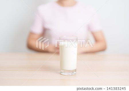 Healthy woman holding glass of fresh milk at home, female drinking milk for calcium and strong bones, high protein, dairy product for healthy lifestyle, wellness and daily routine concept Healthy woman holding glass of fresh milk at home, female drinking milk for calcium and strong bones, high protein, dairy product for healthy lifestyle, wellness and daily routine concept 141383245