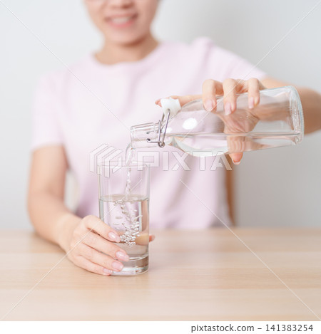 Healthy woman pour clean mineral water into glass at home, female drink pure water for hydration and wellness, fresh skin care, daily routine water intake, Refreshment and lifestyle concept Healthy woman pour clean mineral water into glass at home, female drink pure water for hydration and wellness, fresh skin care, daily routine water intake, Refreshment and lifestyle concept 141383254