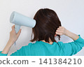 Rear view of a woman drying her hair with a hair dryer 141384210