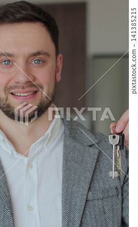 Vertical video Portrait of a happy man real estate agent holding the keys to new apartment. Real estate concept. Vertical video Portrait of a happy man real estate agent holding the keys to new apartment. Real estate concept. 141385215