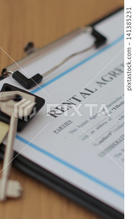 Vertical video Close-up view of a rental agreement document with key, and a pen placed on top. Property rental, leasing contracts, real estate. Vertical video Close-up view of a rental agreement document with key, and a pen placed on top. Property rental, leasing contracts, real estate. 141385231