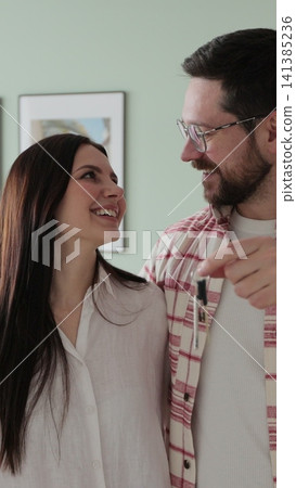 Vertical video Happy couple owners of a new apartment show the key looking at the camera. Buying first family real estate, move in new home. Home buying. Vertical video Happy couple owners of a new apartment show the key looking at the camera. Buying first family real estate, move in new home. Home buying. 141385236