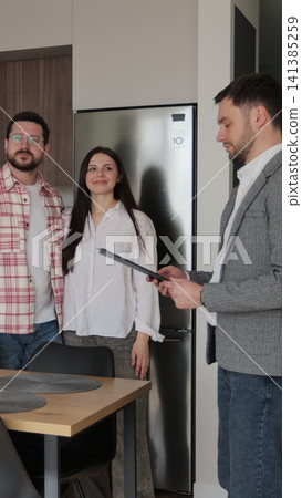 Vertical video Real estate agent man shows modern house to a young couple. Young couple client rent investment. Vertical video Real estate agent man shows modern house to a young couple. Young couple client rent investment. 141385259