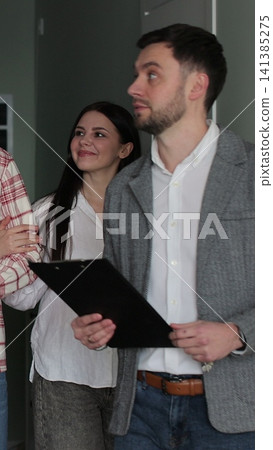 Vertical video Young couple with real-estate agent visiting apartment for sale or for rent. Loving people buying an apartment. Real estate concept. Vertical video Young couple with real-estate agent visiting apartment for sale or for rent. Loving people buying an apartment. Real estate concept. 141385275