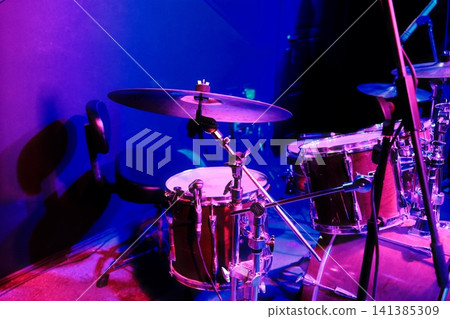 Drum set on stage under purple and blue spotlights Drum set on stage under purple and blue spotlights 141385309