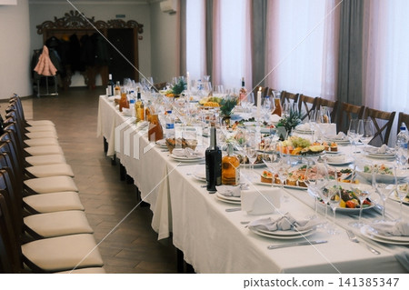 Festive dining table arranged in a spacious event hall Festive dining table arranged in a spacious event hall 141385347