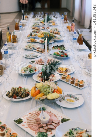 Festive banquet table with various dishes and lit candles Festive banquet table with various dishes and lit candles 141385348