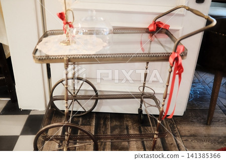Festive vintage brass serving cart with red ribbons Festive vintage brass serving cart with red ribbons 141385366