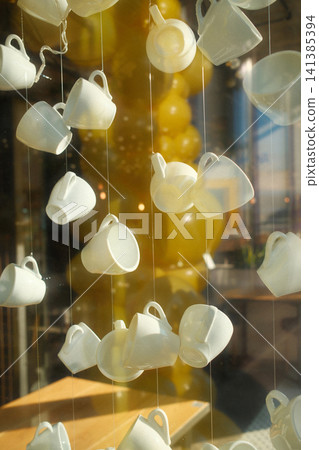 Numerous white cups hanging in a retail window Numerous white cups hanging in a retail window 141385394
