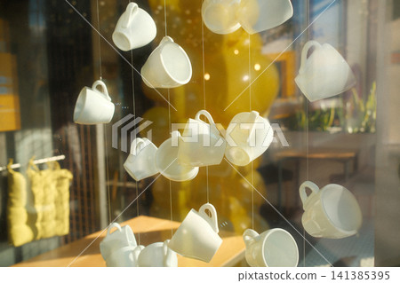 Display of white cups in sunny cafe window 141385395