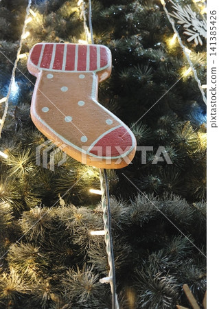 Dotted, striped gingerbread stocking ornament on a green lit tree. Dotted, striped gingerbread stocking ornament on a green lit tree. 141385426