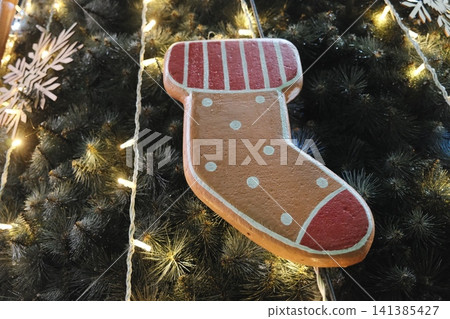Gingerbread stocking on warm-lit dark green tree. 141385427