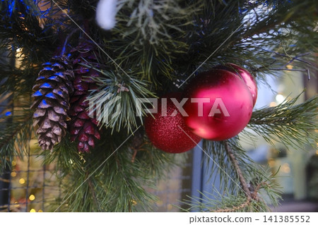 Holiday pine cones and red ornaments in the evening Holiday pine cones and red ornaments in the evening 141385552