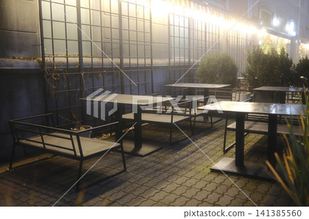 Empty cafe patio at night with metal tables and benches Empty cafe patio at night with metal tables and benches 141385560