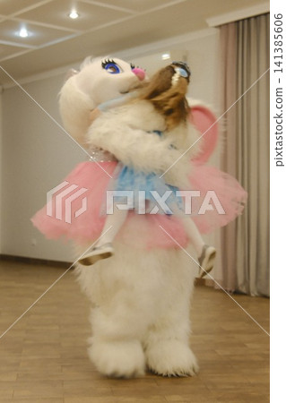 Girl rides piggyback on white furry animal mascot Girl rides piggyback on white furry animal mascot 141385606