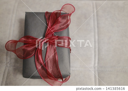 Gray wrapped gift with red ribbon bow 141385616