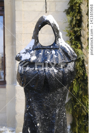 Black abstract metal sculpture resembling a cloaked figure in the snow Black abstract metal sculpture resembling a cloaked figure in the snow 141385668
