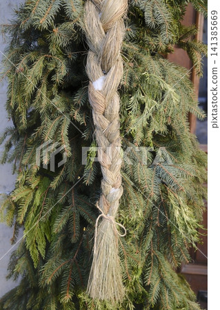 Traditional straw braid decoration hanging on Christmas green fir garland Traditional straw braid decoration hanging on Christmas green fir garland 141385669