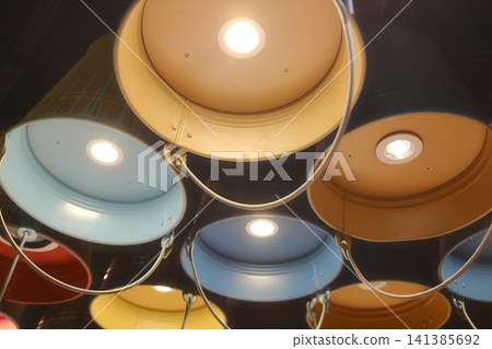 Inverted metal buckets in shades of yellow and blue provide decorative illumination Inverted metal buckets in shades of yellow and blue provide decorative illumination 141385692
