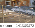 Shiny stainless steel handrails ascend concrete outdoor stairs. 141385872