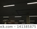 Multiple linear lights illuminate a dark concrete ceiling in an underground parking garage 141385875