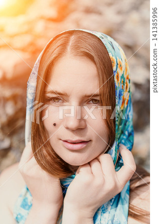 Woman scarf portrait wearing a blue floral headscarf outdoors in the bright sunlight with a soft sun flare Woman scarf portrait wearing a blue floral headscarf outdoors in the bright sunlight with a soft sun flare 141385996