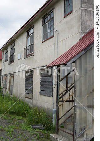 An old apartment complex covered in grass 141386100