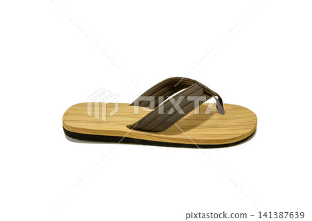 Single wooden flip flop isolated on white background. Eco-friendly summer sandal for beach, travel, resort, retail, product mockup, sustainable fashion, and footwear concepts. Single wooden flip flop isolated on white background. Eco-friendly summer sandal for beach, travel, resort, retail, product mockup, sustainable fashion, and footwear concepts. 141387639