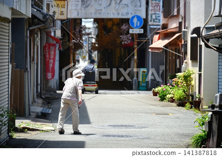 An elderly woman walking in an alley 141387818