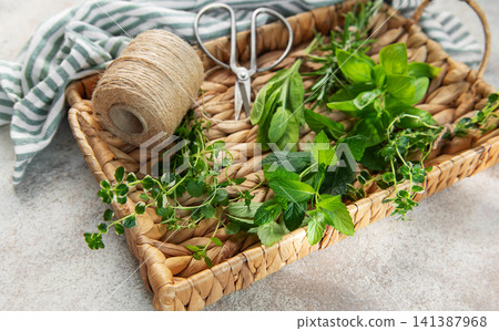 Fresh herbs collected in wicker basket with gardening supplies Fresh herbs collected in wicker basket with gardening supplies 141387968