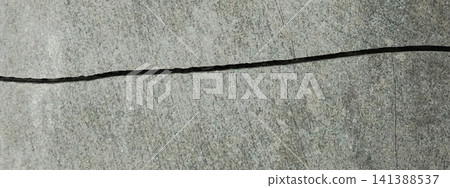 A horizontal crack splits the smooth, gray concrete surface. A horizontal crack splits the smooth, gray concrete surface. 141388537