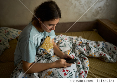 Teen girl using phone in bed morning 141389123