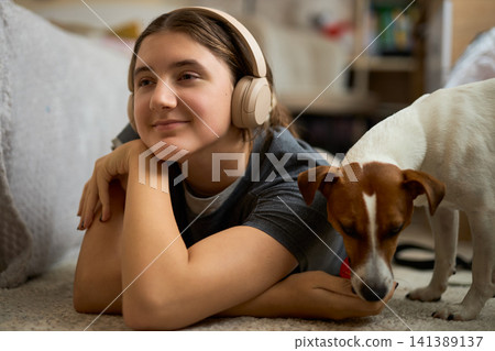Teen girl relaxing with dog and toy Teen girl relaxing with dog and toy 141389137