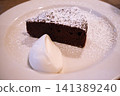 Chocolate cake sprinkled with powdered sugar and whipped cream 141389240