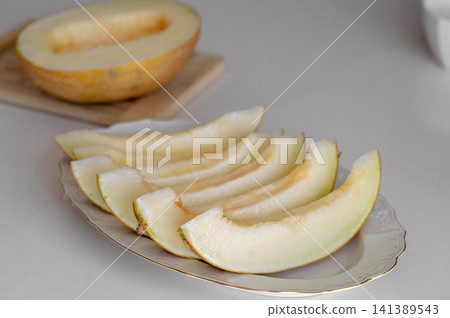 Slices of fresh cantaloupe arranged on a white plate with whole melon in background Slices of fresh cantaloupe arranged on a white plate with whole melon in background 141389543