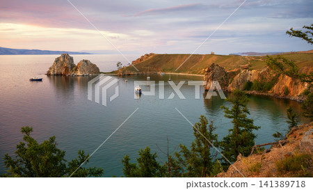 Shamanka Rock on Olkhon Island at Lake Baikal. Scenic sunset landscape of Cape Burkhan in Siberia Russia. Famous natural landmark and travel destination Shamanka Rock on Olkhon Island at Lake Baikal. Scenic sunset landscape of Cape Burkhan in Siberia Russia. Famous natural landmark and travel destination 141389718