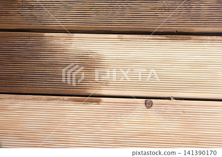 Brown oil for protection of wood by staining. Painting a larch for protecting and pests. Woodworker applying finish to terrace deck board. Repairman varnishing with brush wooden plank floor surface. Brown oil for protection of wood by staining. Painting a larch for protecting and pests. Woodworker applying finish to terrace deck board. Repairman varnishing with brush wooden plank floor surface. 141390170