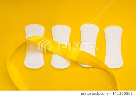 Four Sanitary Pads with Yellow Awareness Ribbon on Yellow Background Four Sanitary Pads with Yellow Awareness Ribbon on Yellow Background 141390861