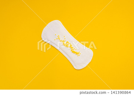 Sanitary Pad with Yellow Beads Symbolising Urinary Leakage on Yellow Background Sanitary Pad with Yellow Beads Symbolising Urinary Leakage on Yellow Background 141390864