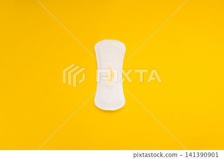 Sanitary Pad with Small Yellow Urine Stain on Yellow Background Sanitary Pad with Small Yellow Urine Stain on Yellow Background 141390901