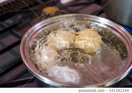 Boiled egg: The image of a raw egg being boiled in hot water. Boiled egg: The image of a raw egg being boiled in hot water. 141391244