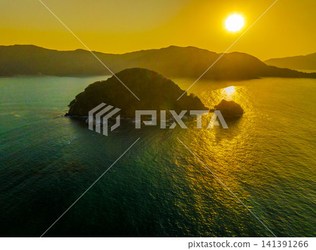 A drone aerial view of the sunset over Karasubejima Island in Sekumi, Wakasa Town, Fukui Prefecture, and Wakasa Bay. A drone aerial view of the sunset over Karasubejima Island in Sekumi, Wakasa Town, Fukui Prefecture, and Wakasa Bay. 141391266