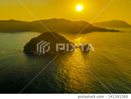 A drone aerial view of the sunset over Karasubejima Island in Sekumi, Wakasa Town, Fukui Prefecture, and Wakasa Bay. A drone aerial view of the sunset over Karasubejima Island in Sekumi, Wakasa Town, Fukui Prefecture, and Wakasa Bay. 141391268
